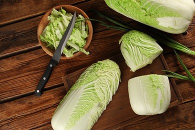 Photo of Fresh ripe Chinese cabbages and green onion on wooden table, flat lay