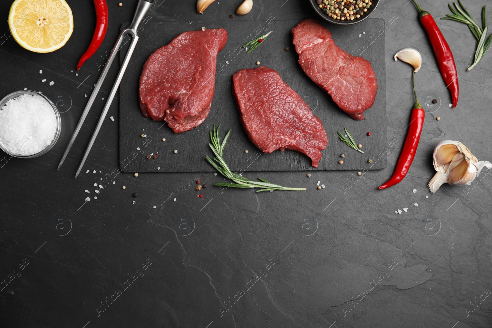 Photo of Fresh raw meat steaks and spices on black table, flat lay. Space for text