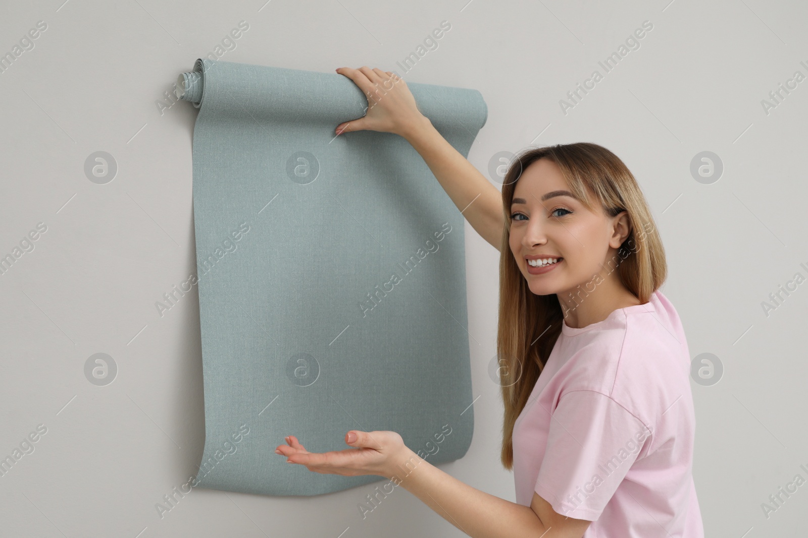 Photo of Happy woman with new wall paper on grey background