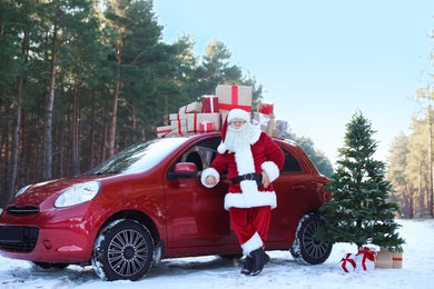Authentic Santa Claus near red car with gift boxes and Christmas tree, outdoors