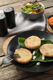 Plate with healthy dish high in vegetable fats and fork on wooden table, closeup