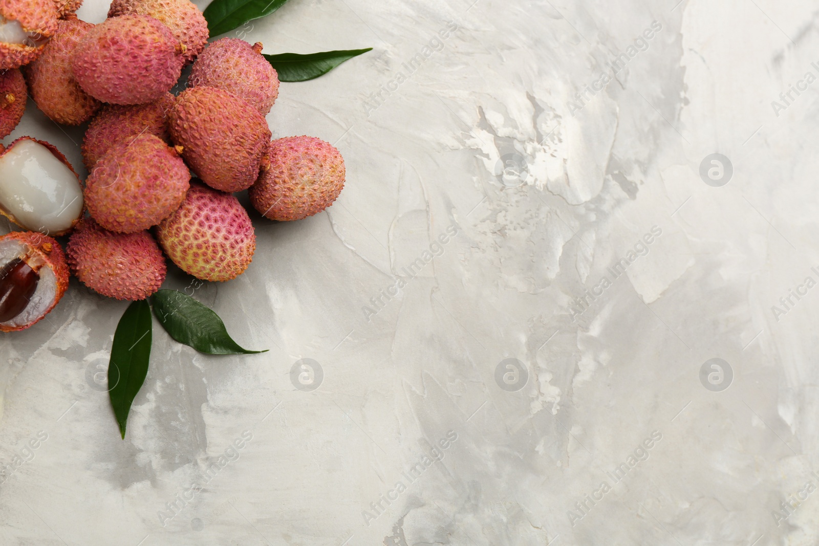 Photo of Fresh ripe lychee fruits on light grey table, flat lay. Space for text