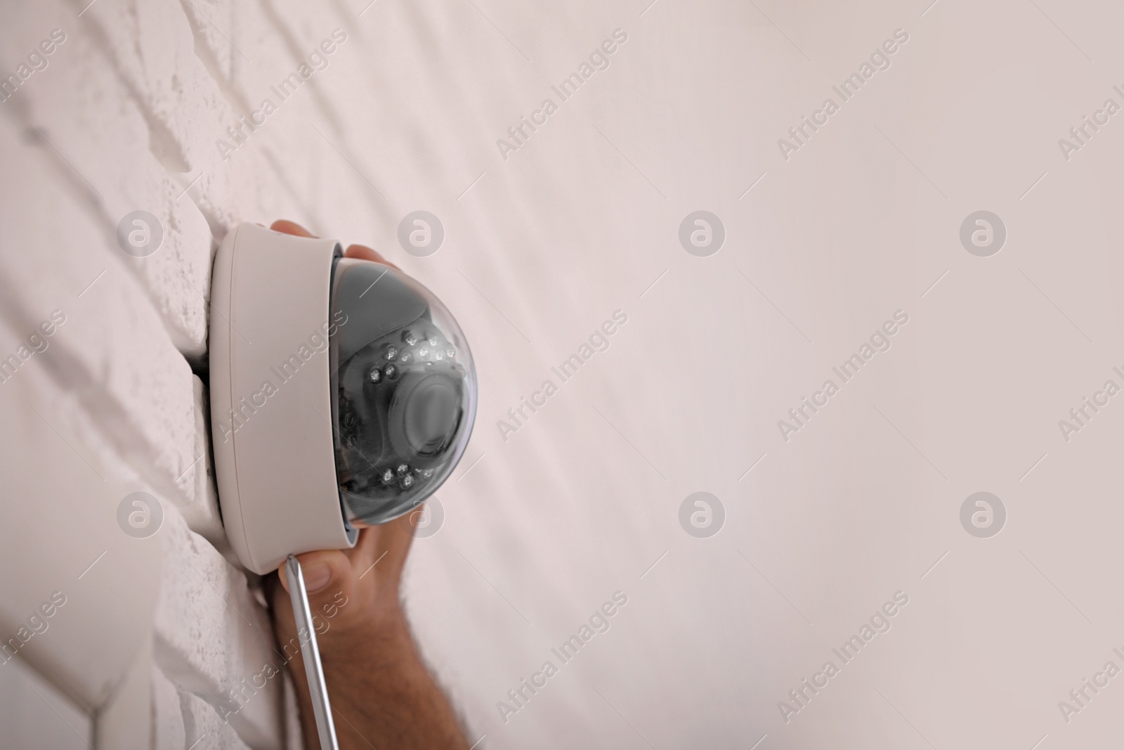 Photo of Technician installing CCTV camera on wall, closeup. Space for text