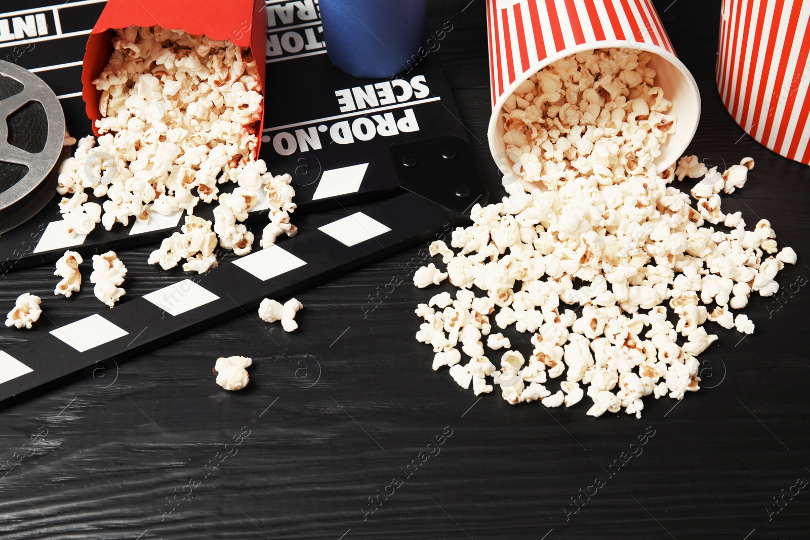 Photo of Tasty popcorn and clapperboard on wooden table. Cinema snack