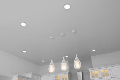 Photo of Ceiling with modern lamps and furniture in stylish kitchen, low angle view