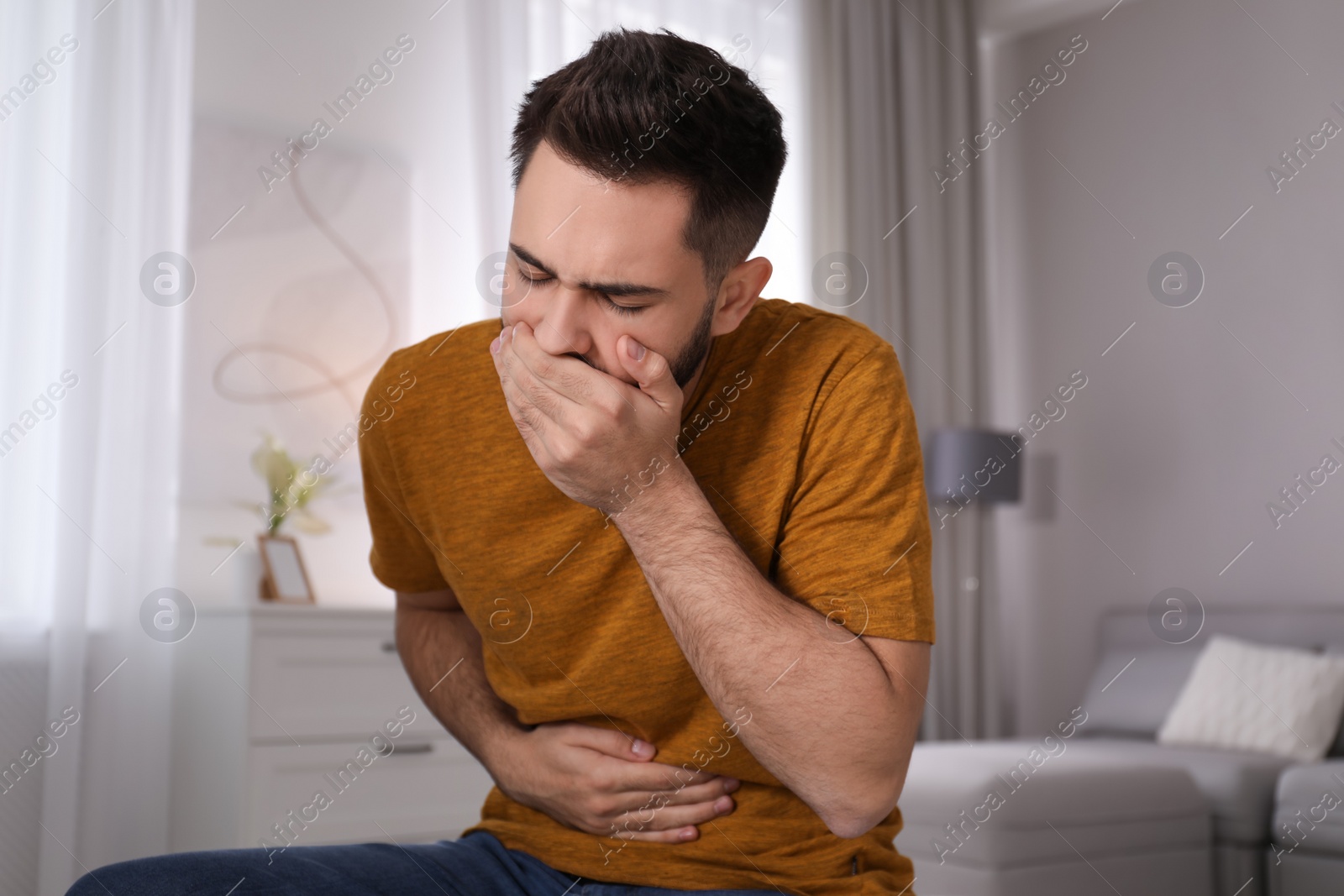 Photo of Young man suffering from nausea at home. Food poisoning