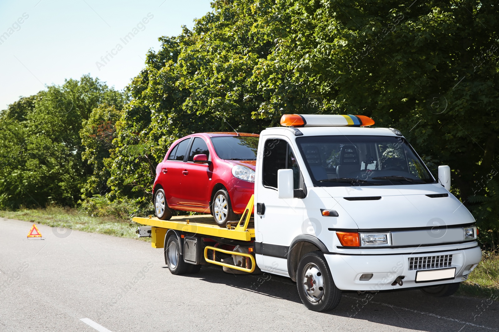 Photo of Tow truck with broken car on country road. Space for text