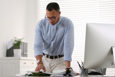 Photo of Businessman working with documents at wooden table in office