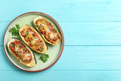 Flat lay composition with delicious stuffed zucchini on light blue wooden table. Space for text