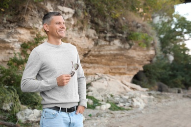 Photo of Man in stylish sweater near old cliff