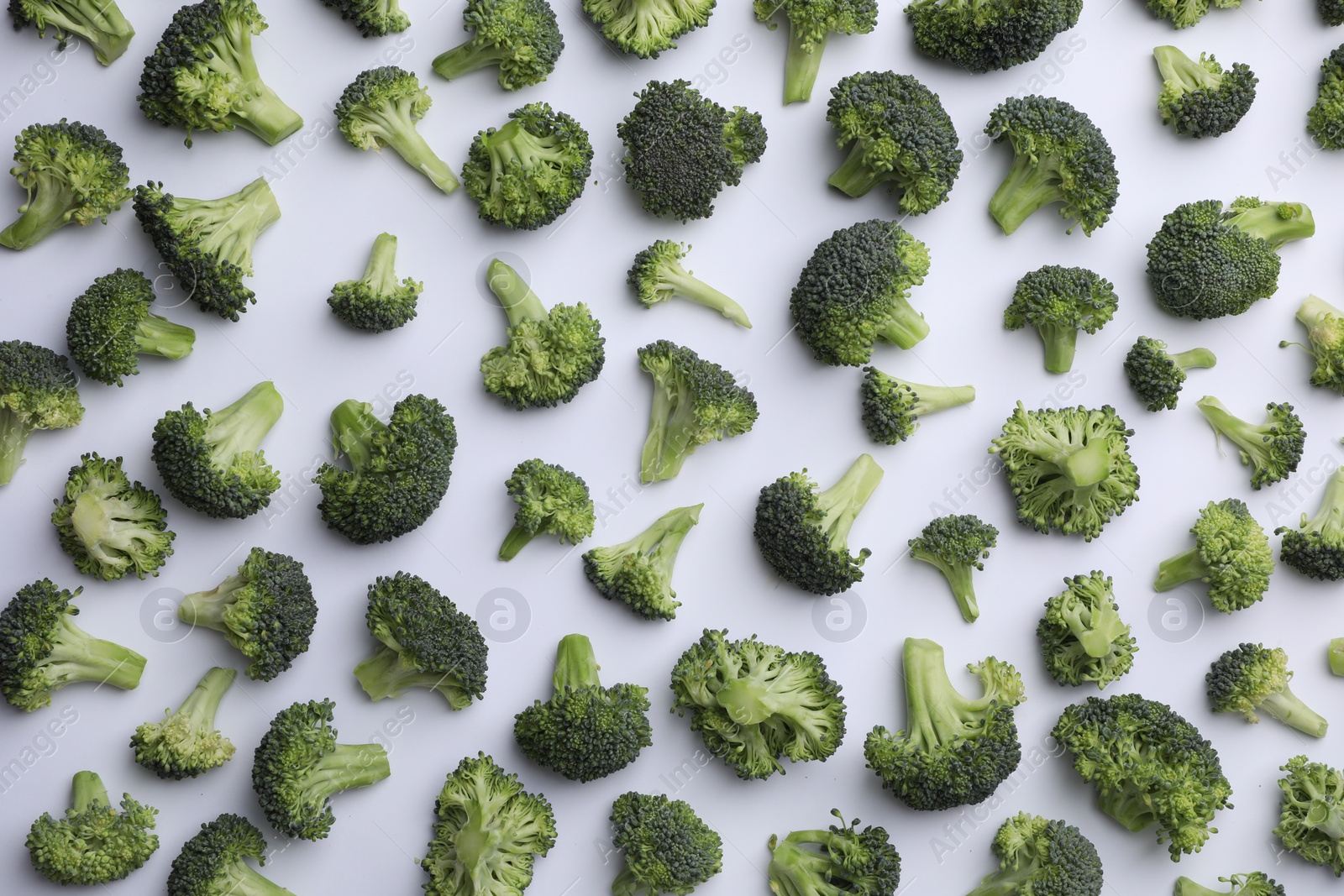 Photo of Many fresh green broccoli pieces on white background, flat lay