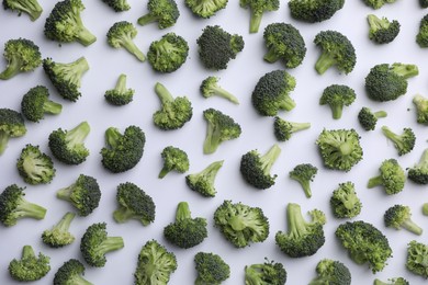 Many fresh green broccoli pieces on white background, flat lay