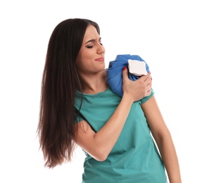 Woman with cold compress suffering from shoulder pain on white background