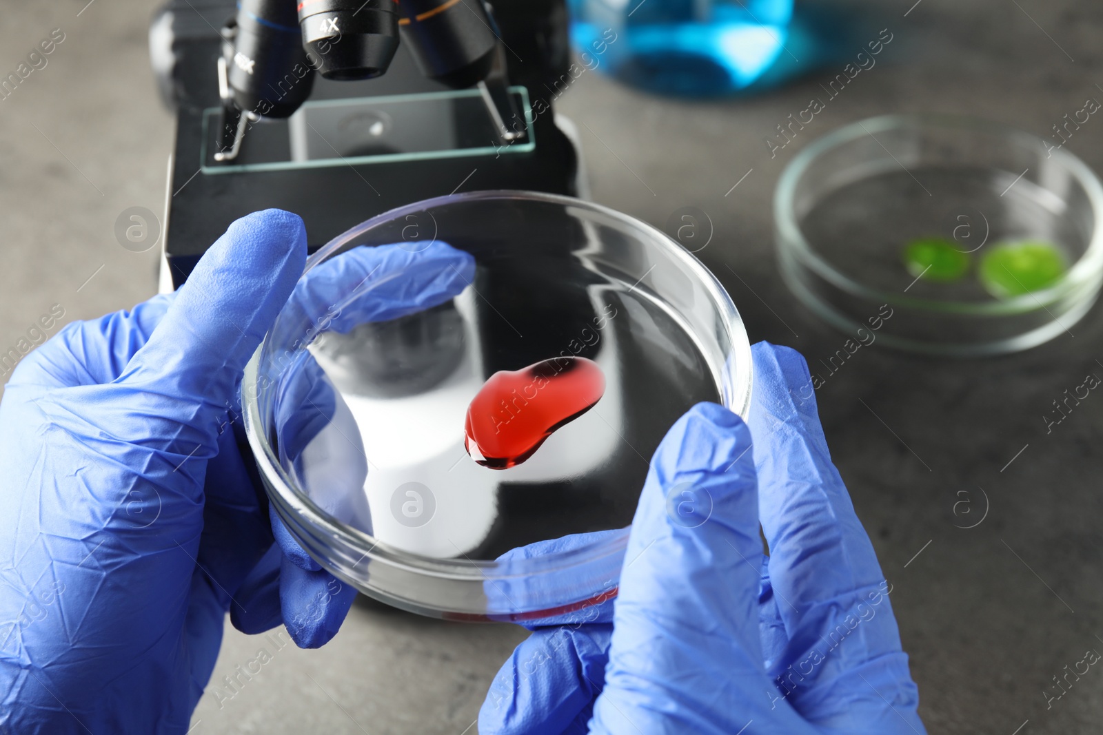 Photo of Medical assistant holding laboratory glassware with sample at table, closeup