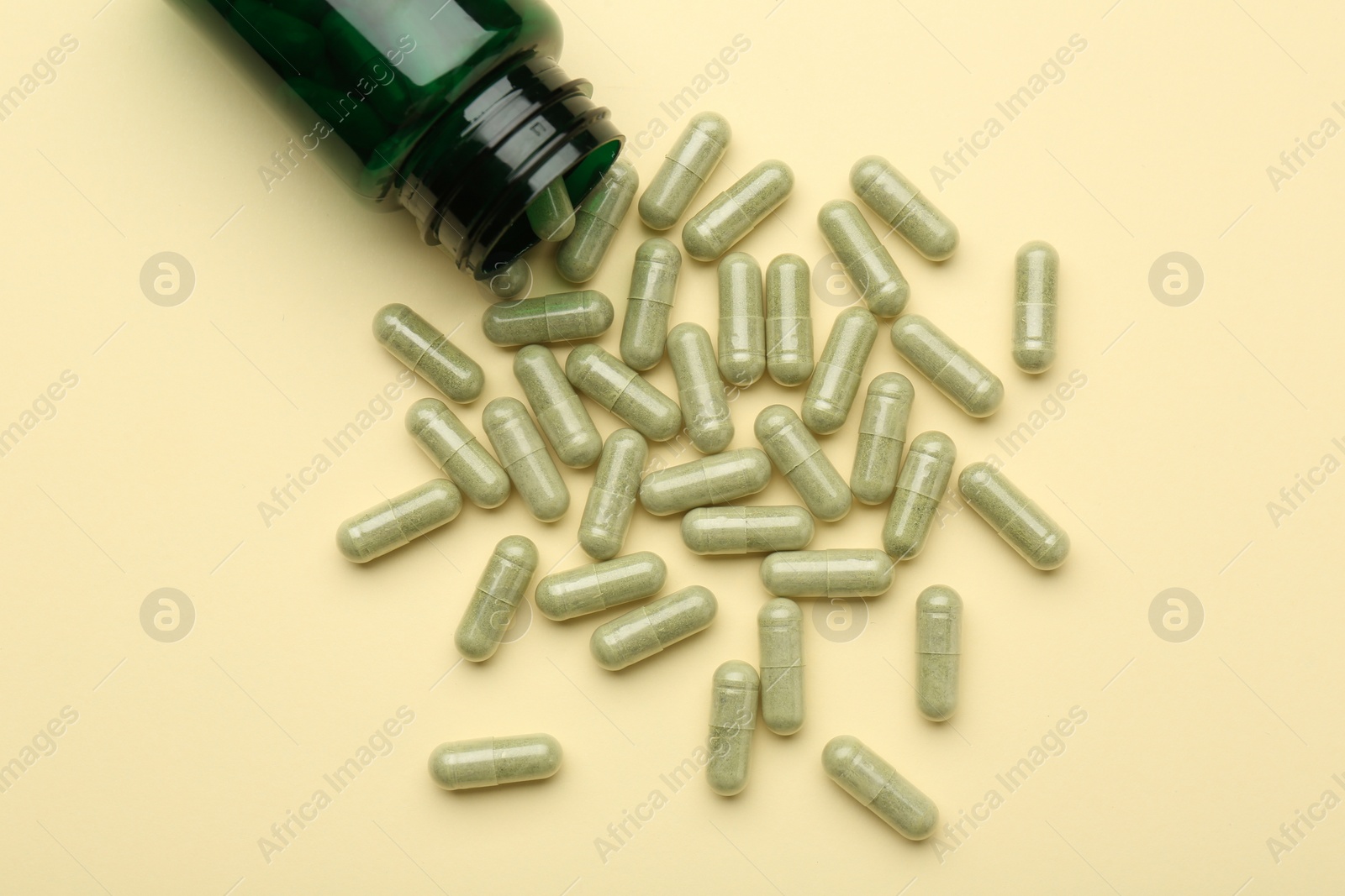 Photo of Vitamin pills and bottle on beige background, top view