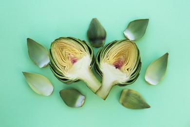 Cut fresh raw artichoke on pale turquoise background, flat lay