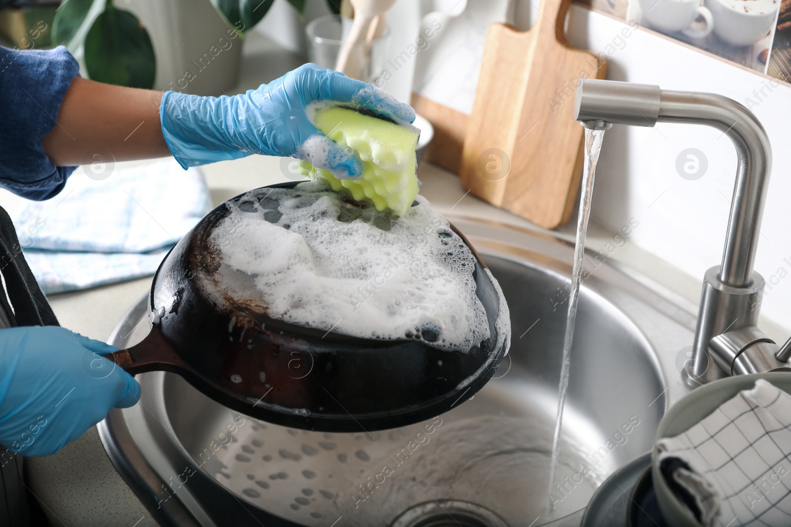 Photo of Woman washing dirty frying pan in sink indoors, closeup