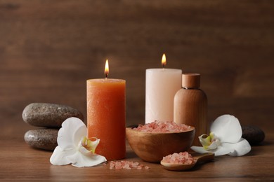 Photo of Beautiful spa composition with sea salt, burning candles and flowers on wooden table