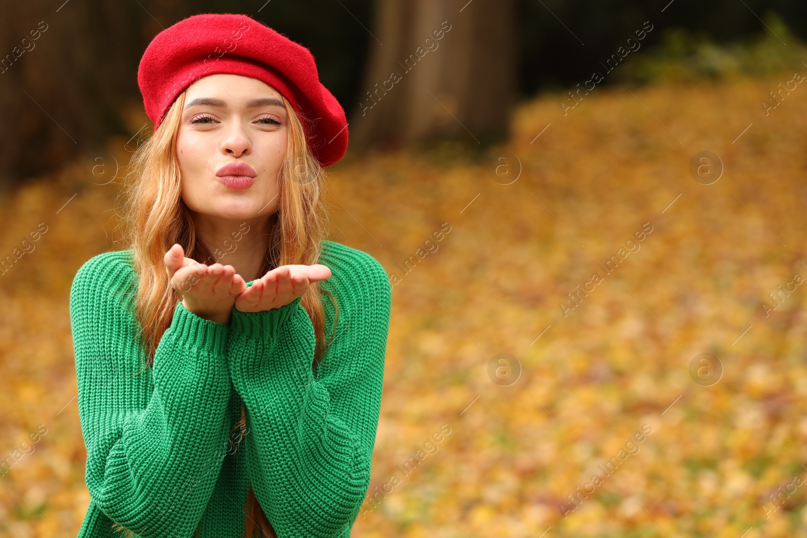 Photo of Portrait of beautiful woman blowing kiss in autumn park. Space for text