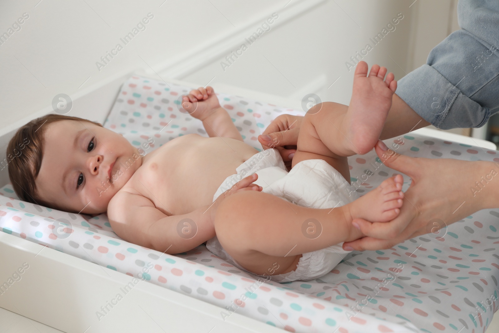 Photo of Mother changing baby's diaper on table at home, closeup