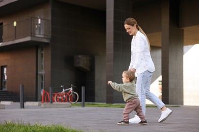 Photo of Happy nanny walking with cute little boy outdoors, space for text