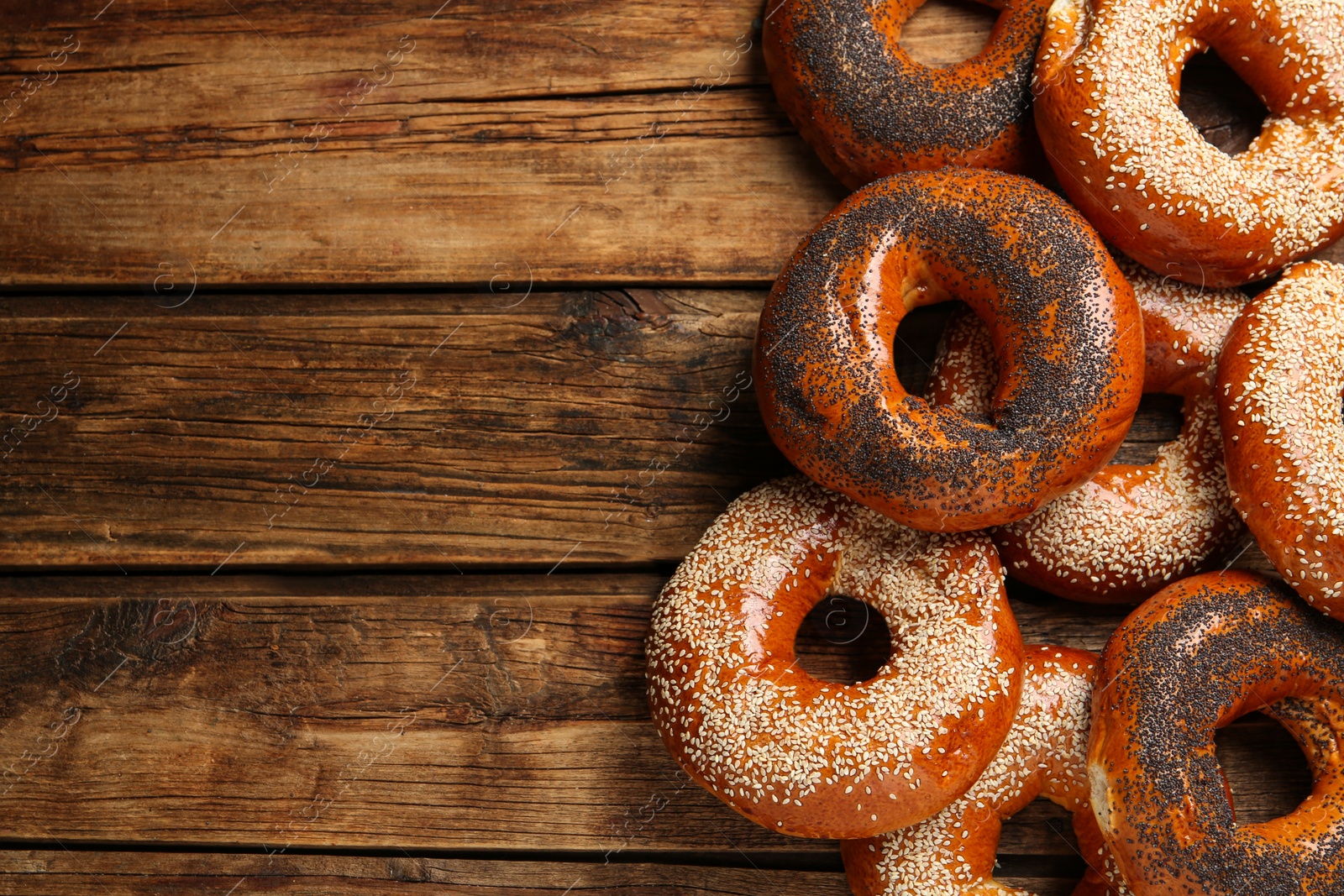 Photo of Many delicious fresh bagels on wooden table, flat lay. Space for text