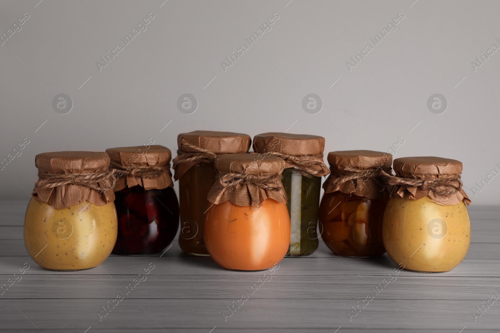 Photo of Jars with preserved fruit jams on white wooden table