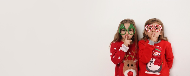 Photo of Kids in Christmas sweaters and festive glasses on white background