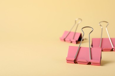 Photo of Binder clips on beige background, closeup. Space for text