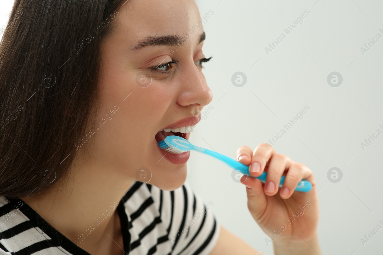 Photo of Woman brushing her teeth with plastic toothbrush on white background, closeup