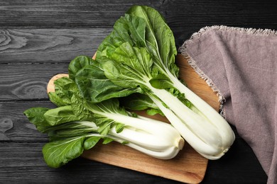 Photo of Fresh green pak choy cabbages on black wooden table, top view
