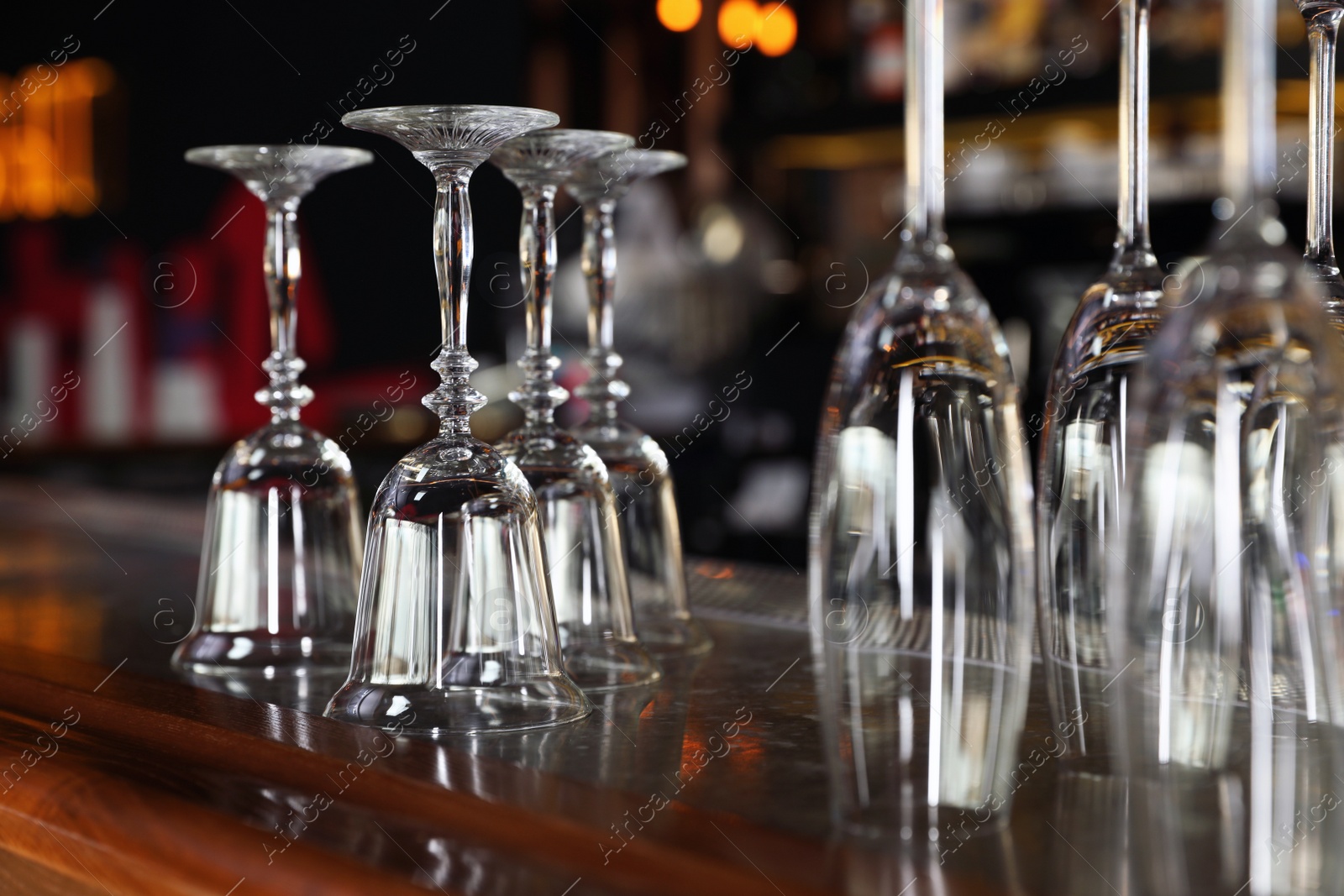 Photo of Different empty clean glasses on counter in bar