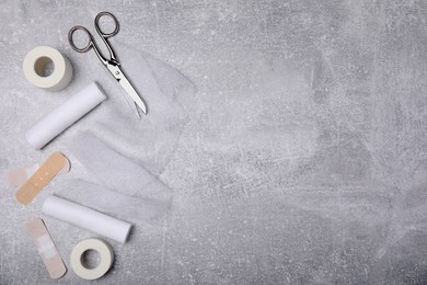 Photo of White bandage rolls and medical supplies on light grey table, flat lay. Space for text
