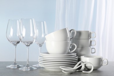 Set of clean dishware and glasses on grey marble table