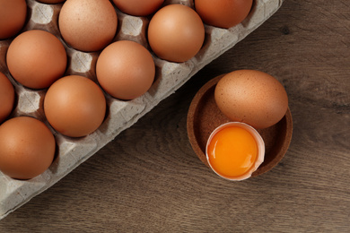 Raw chicken eggs on wooden table, flat lay