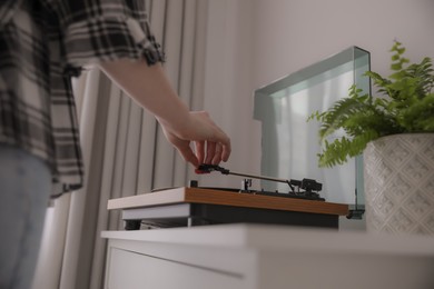 Young woman using turntable at home, closeup