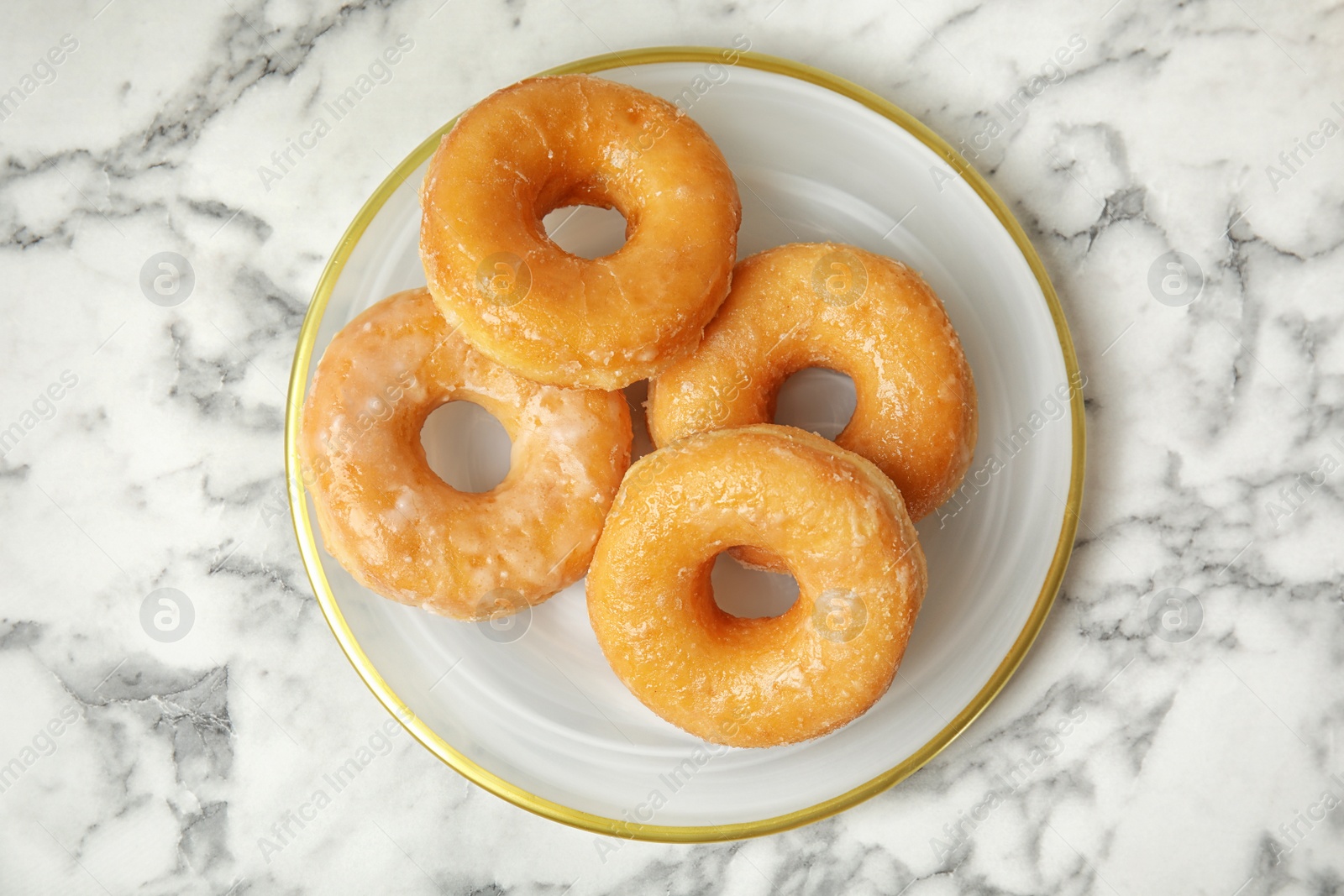 Photo of Delicious donuts on marble table, top view