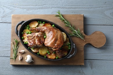 Photo of Tasty cooked rabbit with vegetables in baking dish on grey wooden table, top view