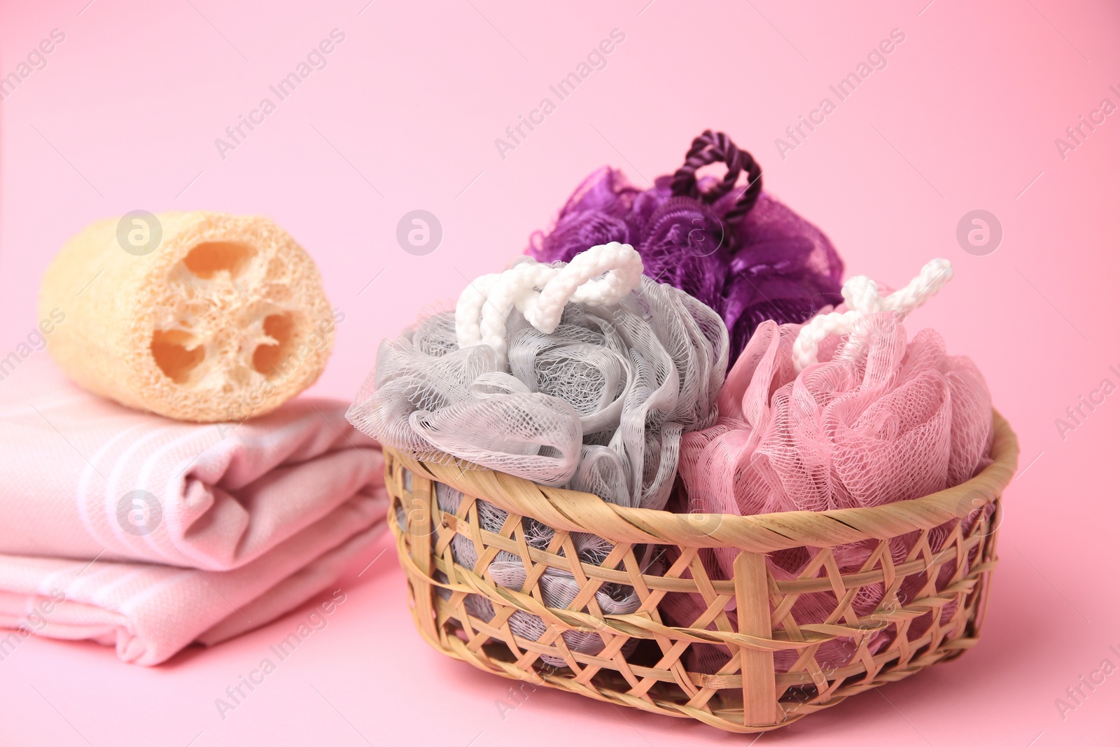 Photo of Wicker basket with colorful shower puffs on pink background