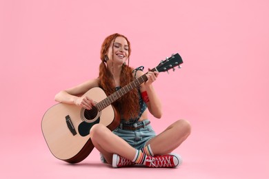 Photo of Stylish young hippie woman playing guitar on pink background