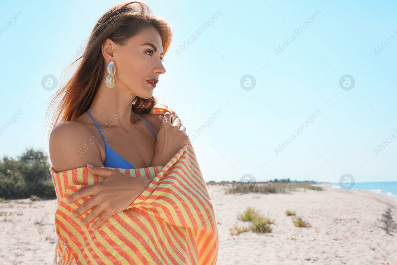 Photo of Beautiful woman with beach towel on sandy seashore