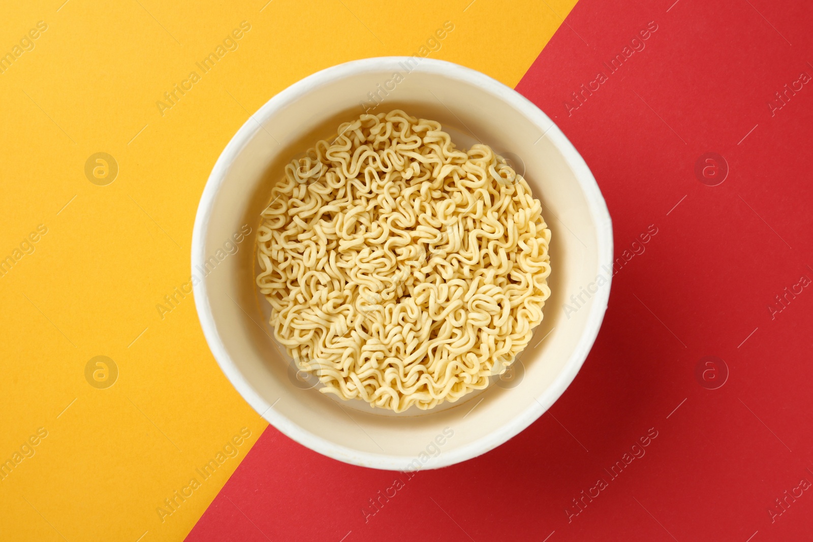 Photo of Cup of instant noodles on color background, top view