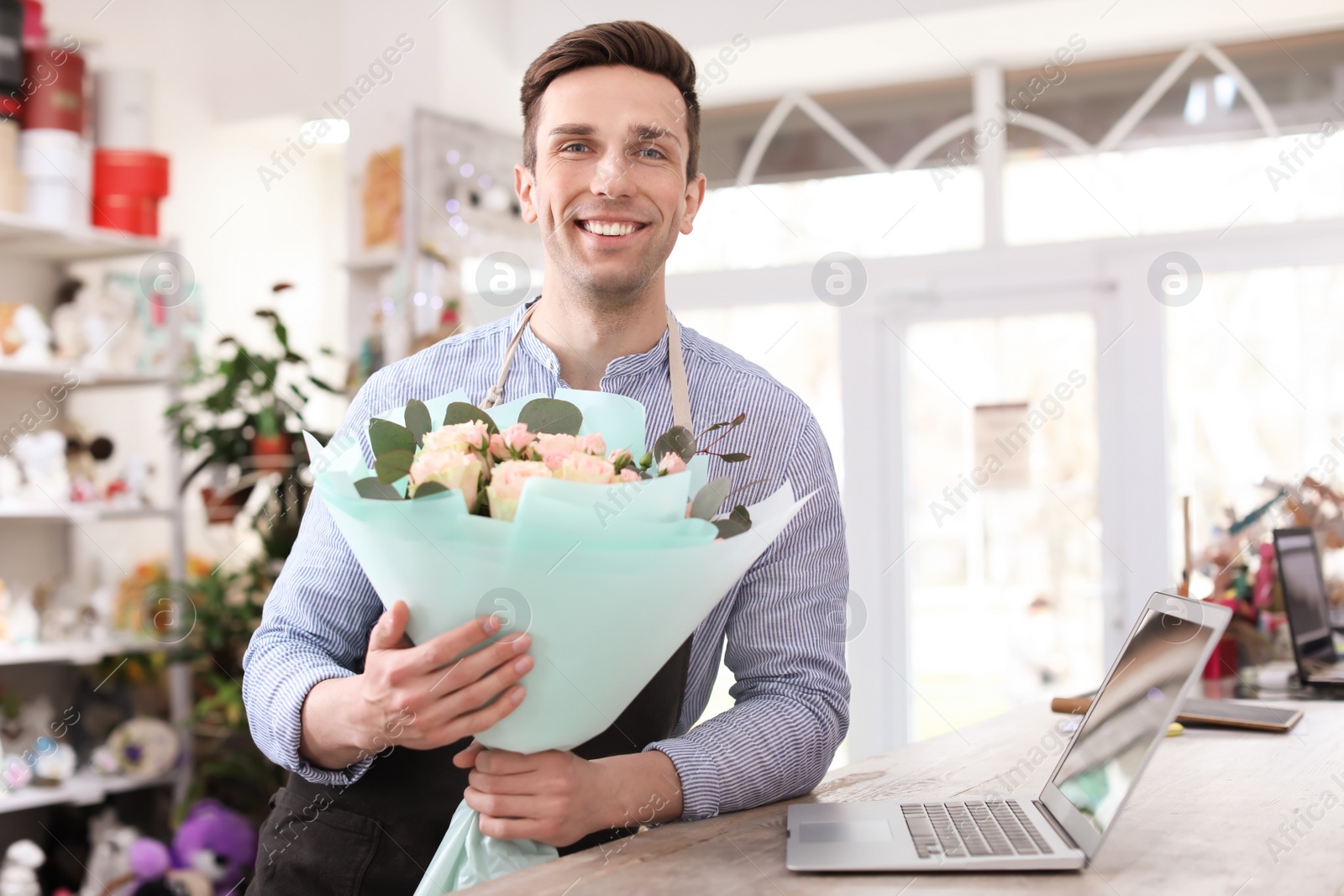 Photo of Male florist holding bouquet flowers at workplace