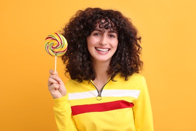 Beautiful woman with lollipop on yellow background