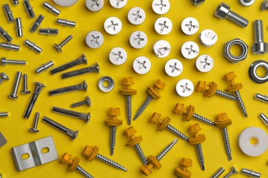 Photo of Many different fasteners on yellow background, flat lay