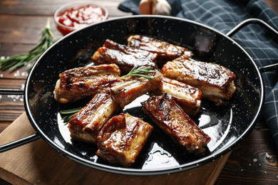 Photo of Delicious grilled ribs with rosemary on wooden table