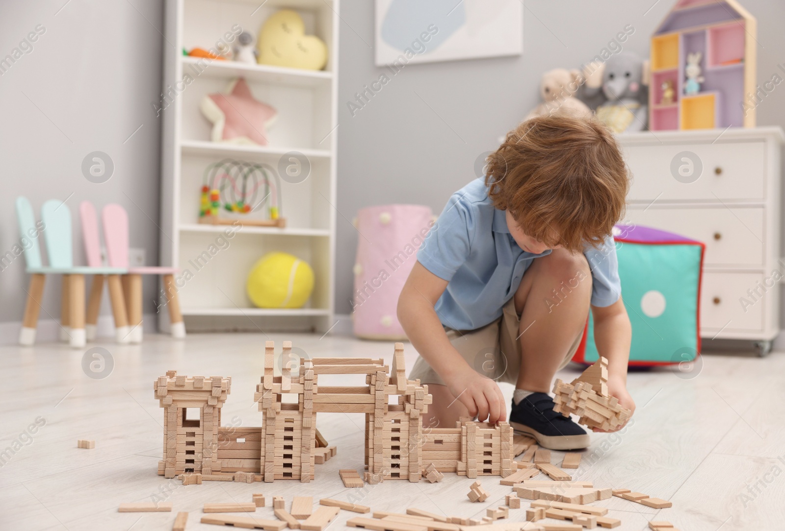 Photo of Little boy playing with wooden construction set on floor in room, space for text. Child's toy