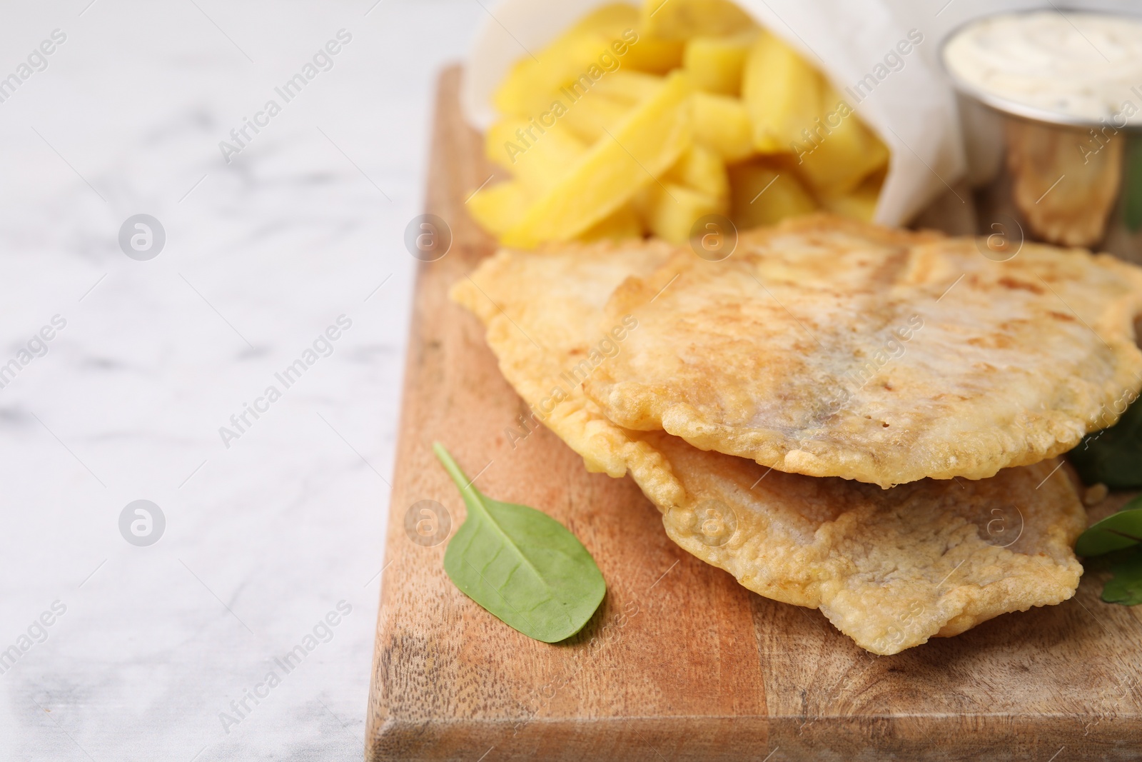 Photo of Delicious fish and chips on white marble table, closeup. Space for text