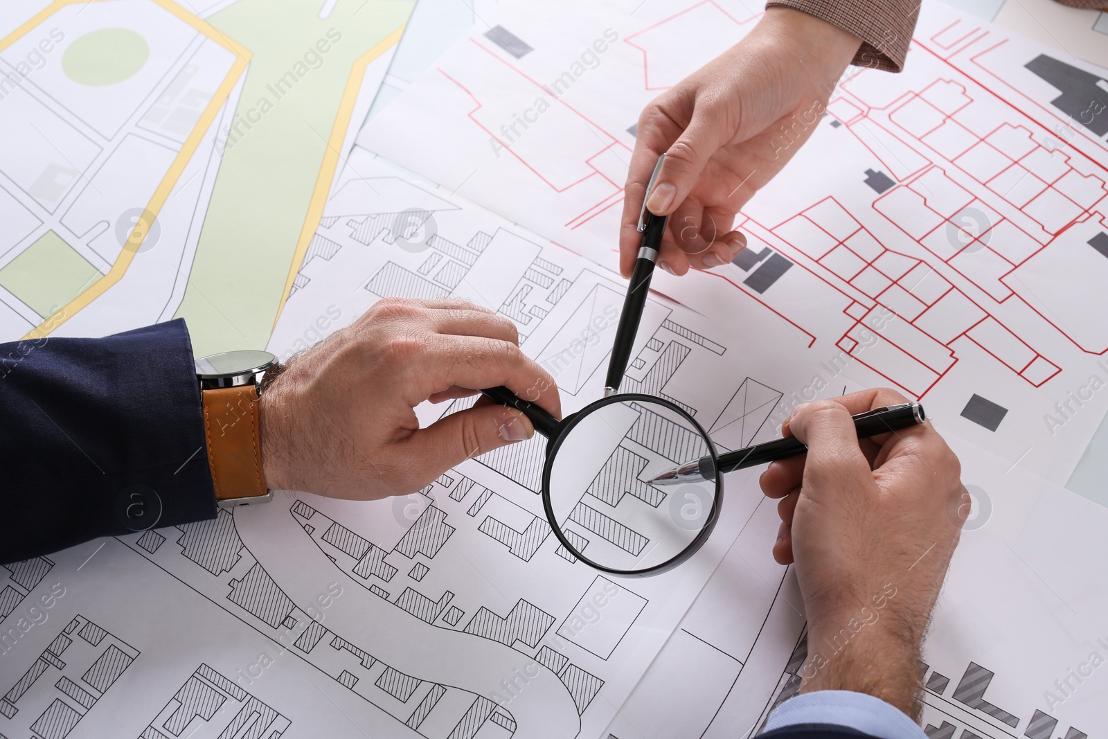 Photo of Professional cartographers working with cadastral map at table, closeup