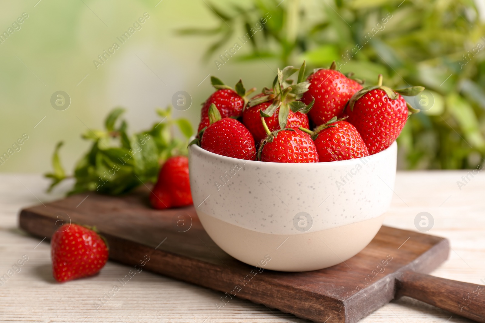 Photo of Bowl with ripe red strawberries on table